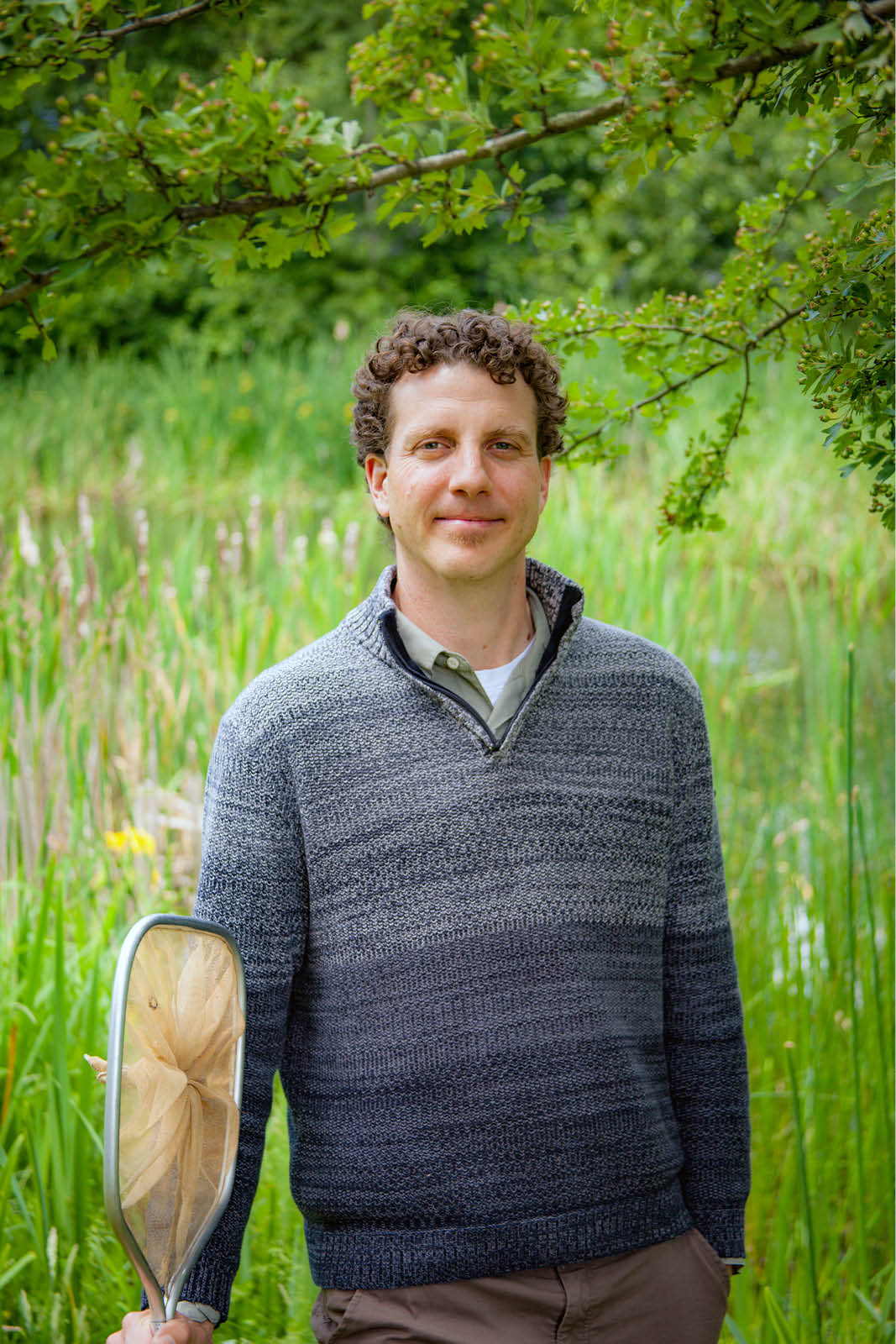 A WSU Vancouver instructor or researcher standing in a green field with trees behind him