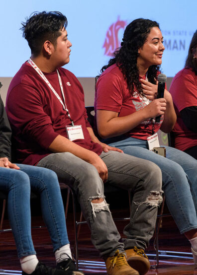 Two women smiling and conversing during an indoor academic event on campus