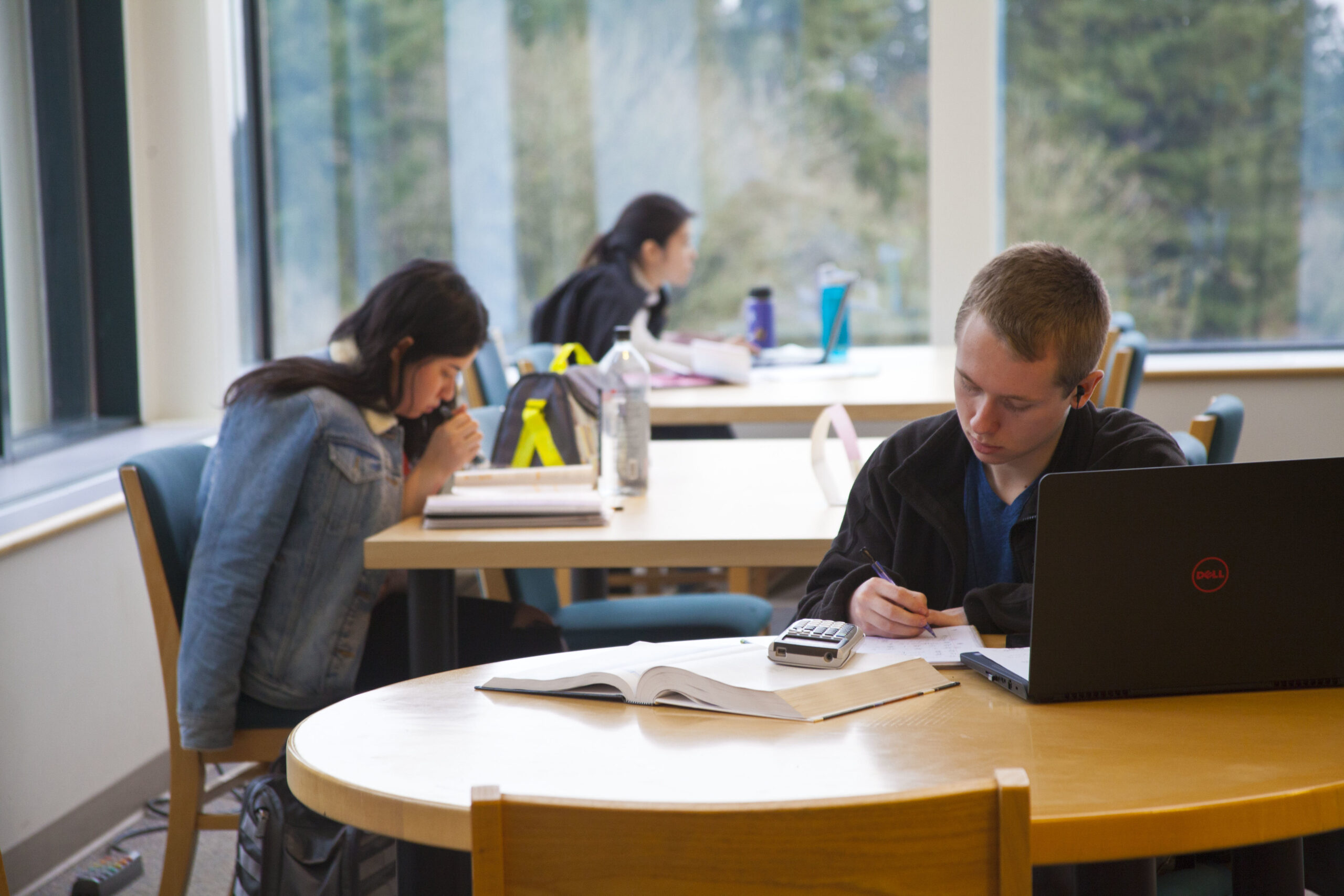 Students reading notes and studying together at a wooden table in a WSU Vancouver lounge