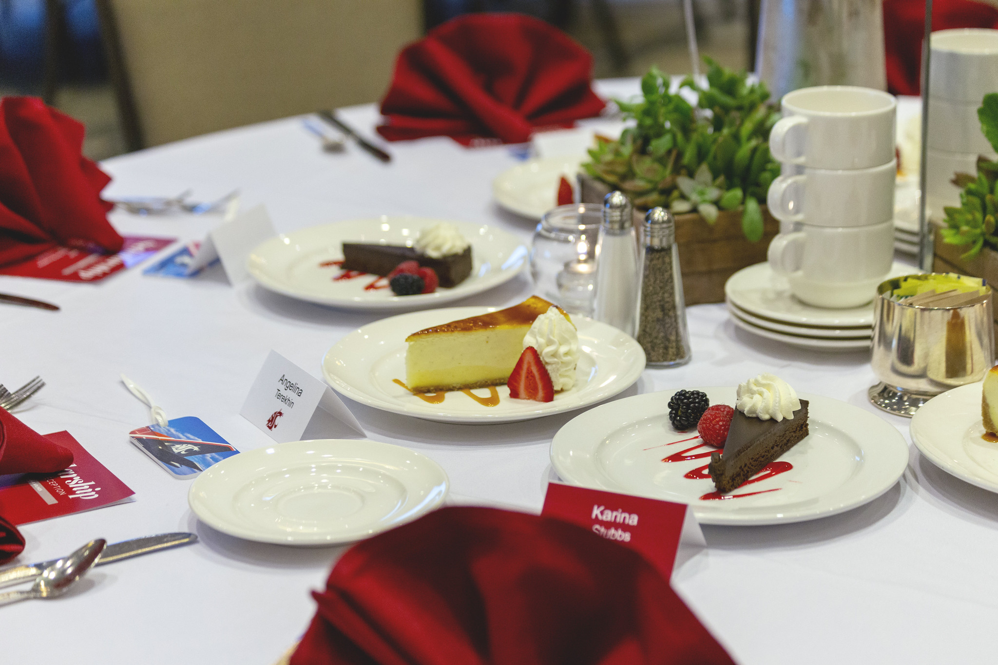 The Notable Alumni Award at WSU Vancouver A beautifully set formal banquet dinner table with white plates, red napkins, and dessert cake slices