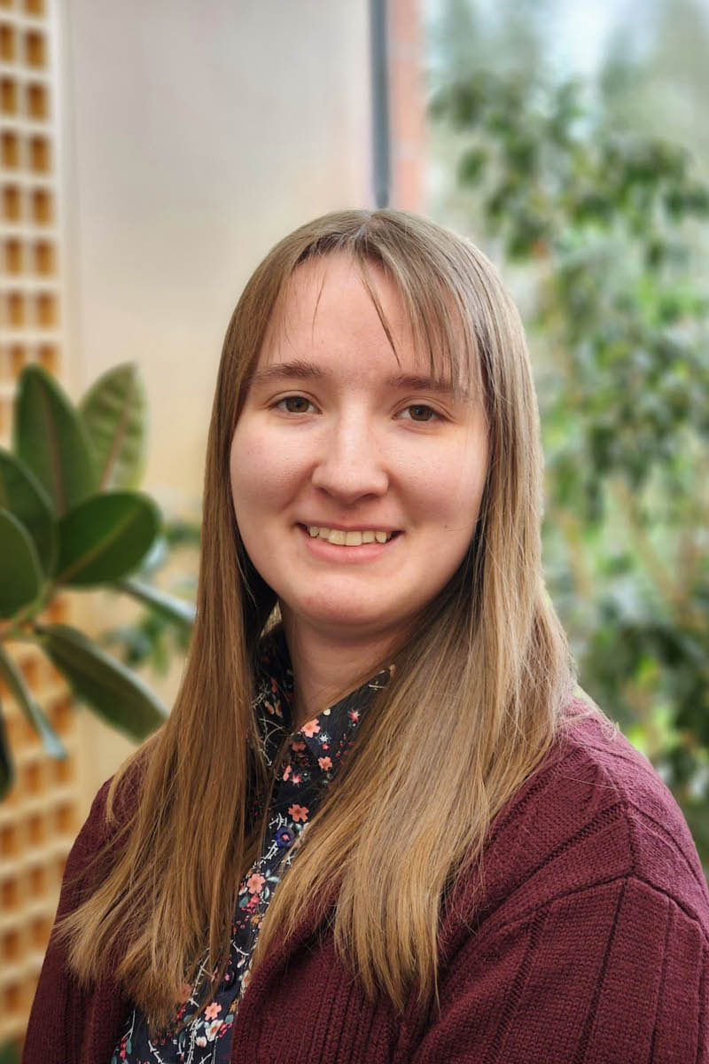 Portrait of a smiling woman with long brown hair inside a WSU Vancouver office space