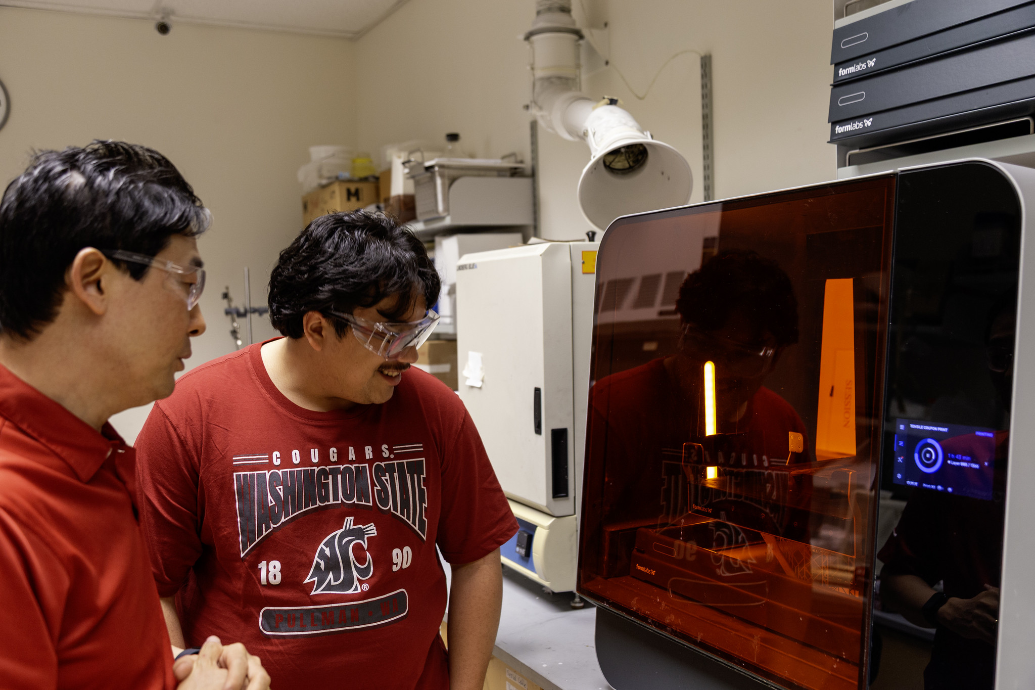A WSU Vancouver engineering student working with equipment next to a 3D printer