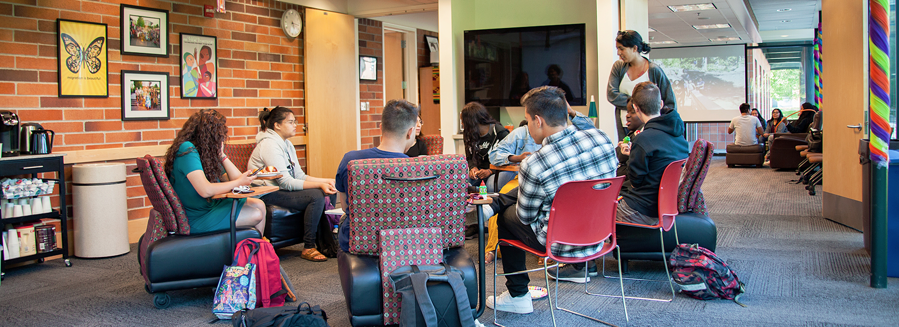 Students and faculty gathering outdoors around picnic tables for a social discussion on campus