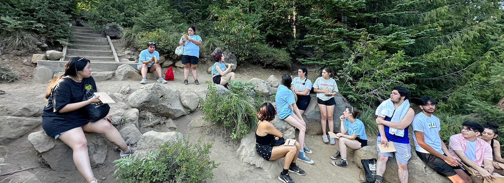 A group of students sitting on the grass lawn together during an outdoor campus social