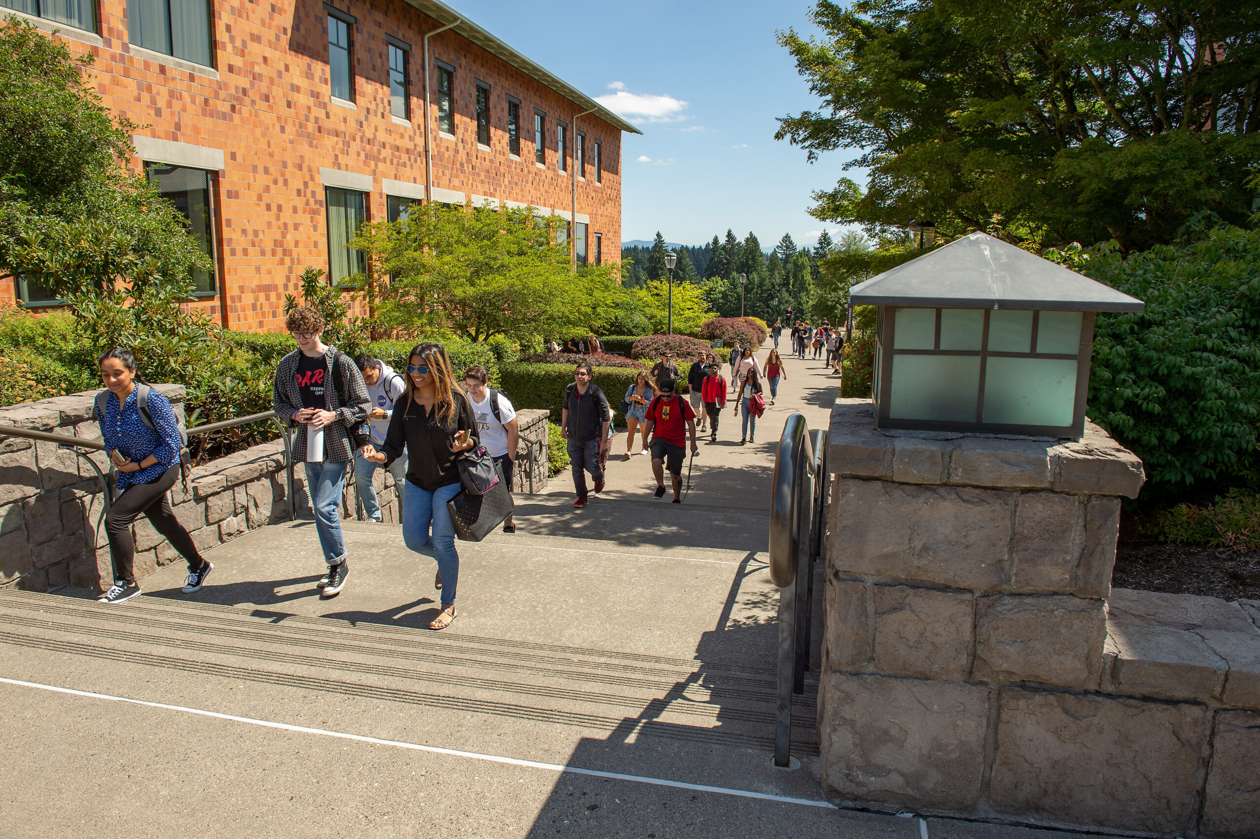 Students walking along a paved pathway on campus next to brick buildings
