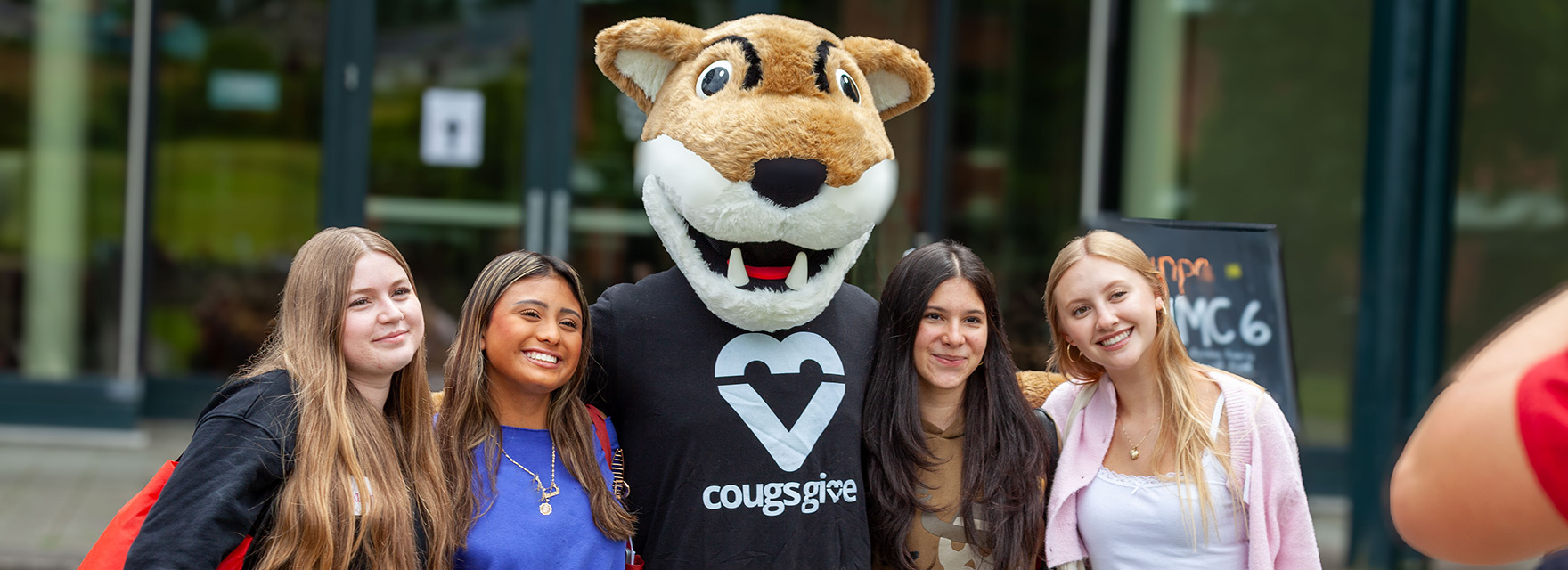 Students posing for a photo with Butch, the WSU mascot, during an outdoor campus gathering