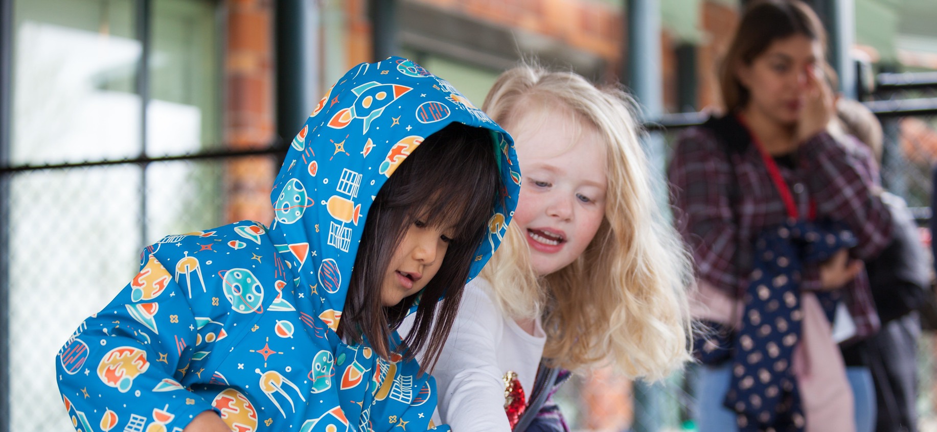 Child-Care Two young children wearing matching blue rain jackets laughing and playing outdoors