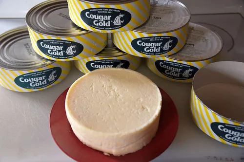 A stack of round metal tins containing the famous Washington State University Cougar Gold cheese product