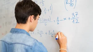A student writing complex mathematical equations on a whiteboard