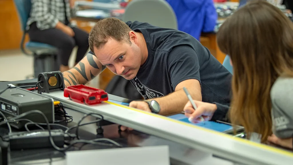 An engineering technician working precisely on a linear alignment rail machine at WSU Vancouver