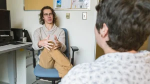 A man in a casual outfit sitting and talking in an office or lounge space