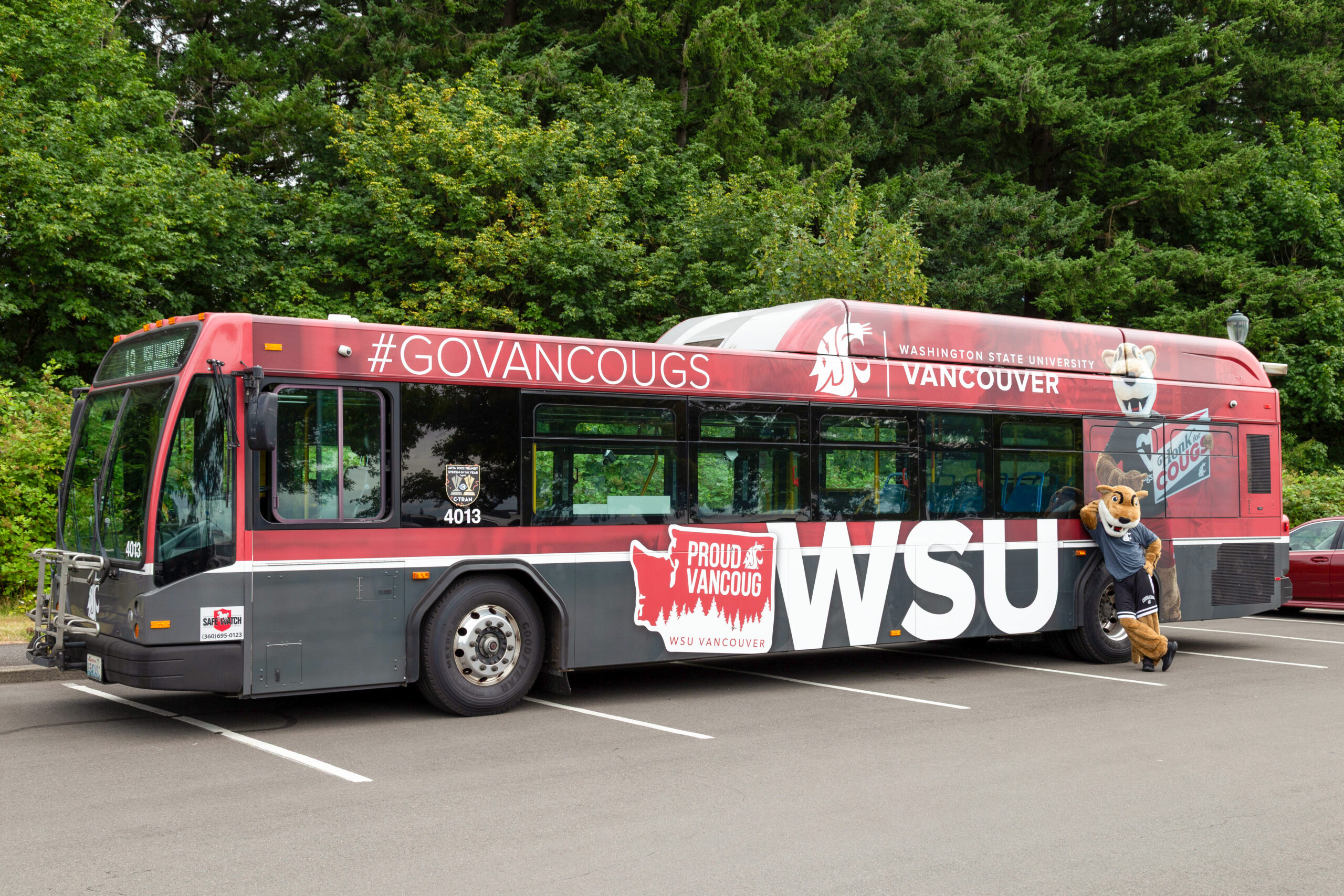 A red WSU Vancouver campus shuttle bus parked at an outdoor transit stop