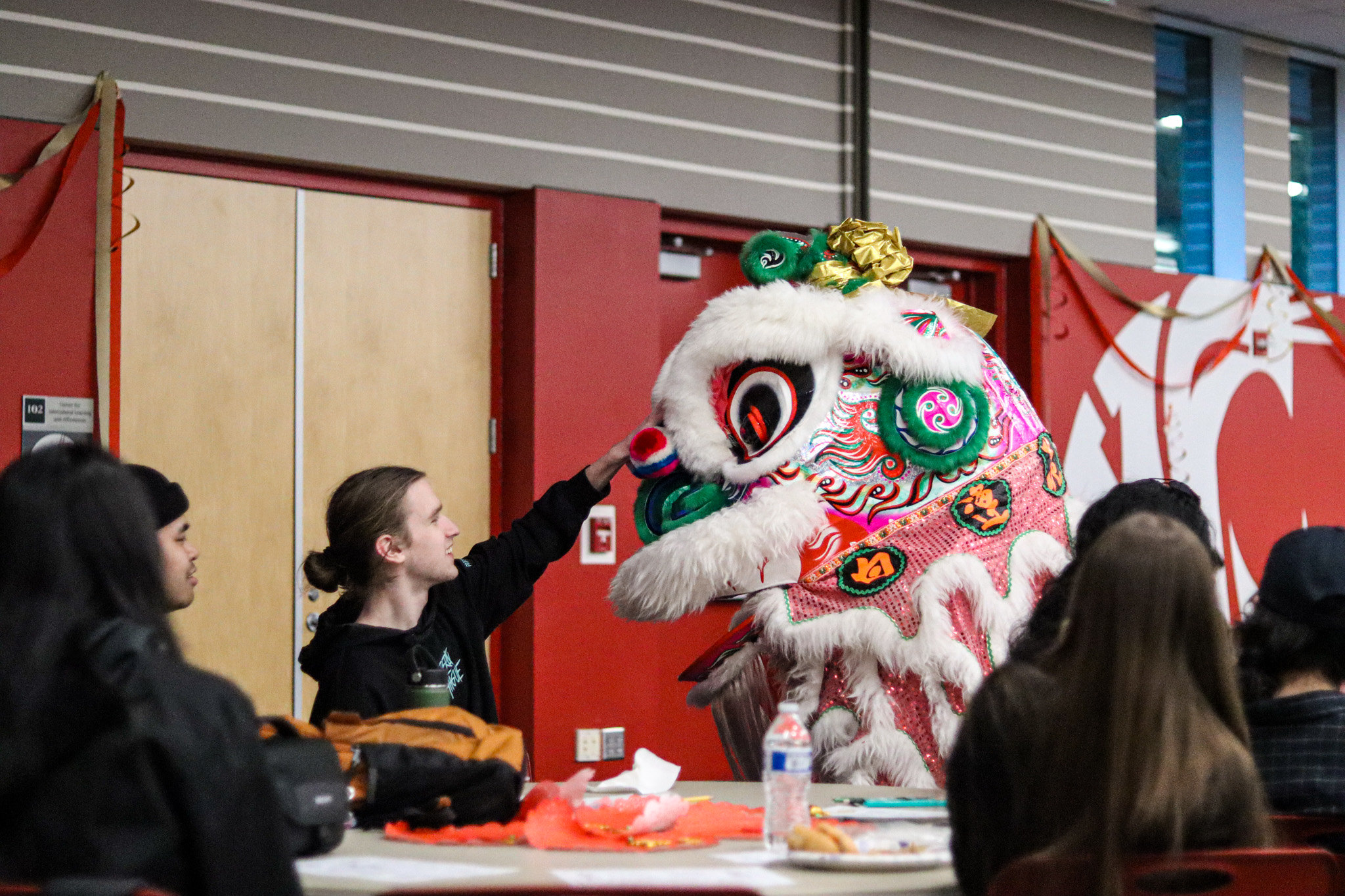 People interacting with a dynamic red and white parade dragon costume