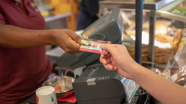 A cashier scanning a card at a point-of-sale register terminal inside a campus store