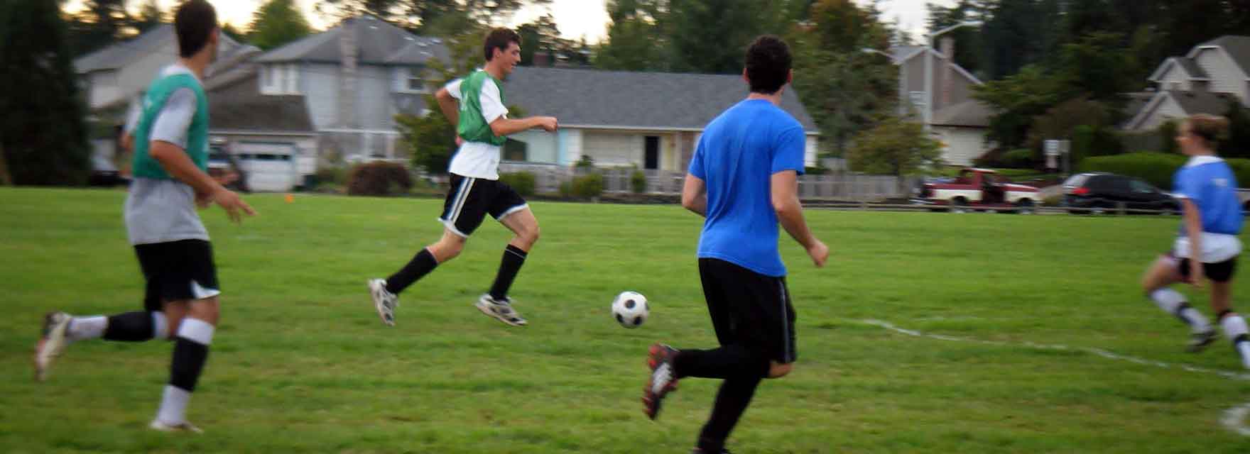 Two soccer players running and competing for a ball during an outdoor match on a green sports field
