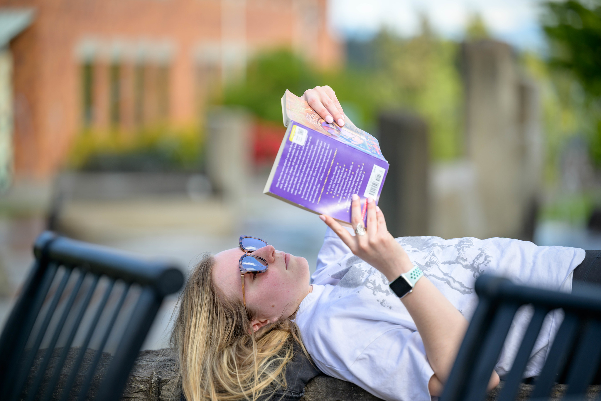 A student relaxing on the WSU Vancouver campus lawn while holding a folder over their face