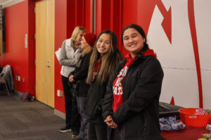 A group of students standing together next to a red wall mural