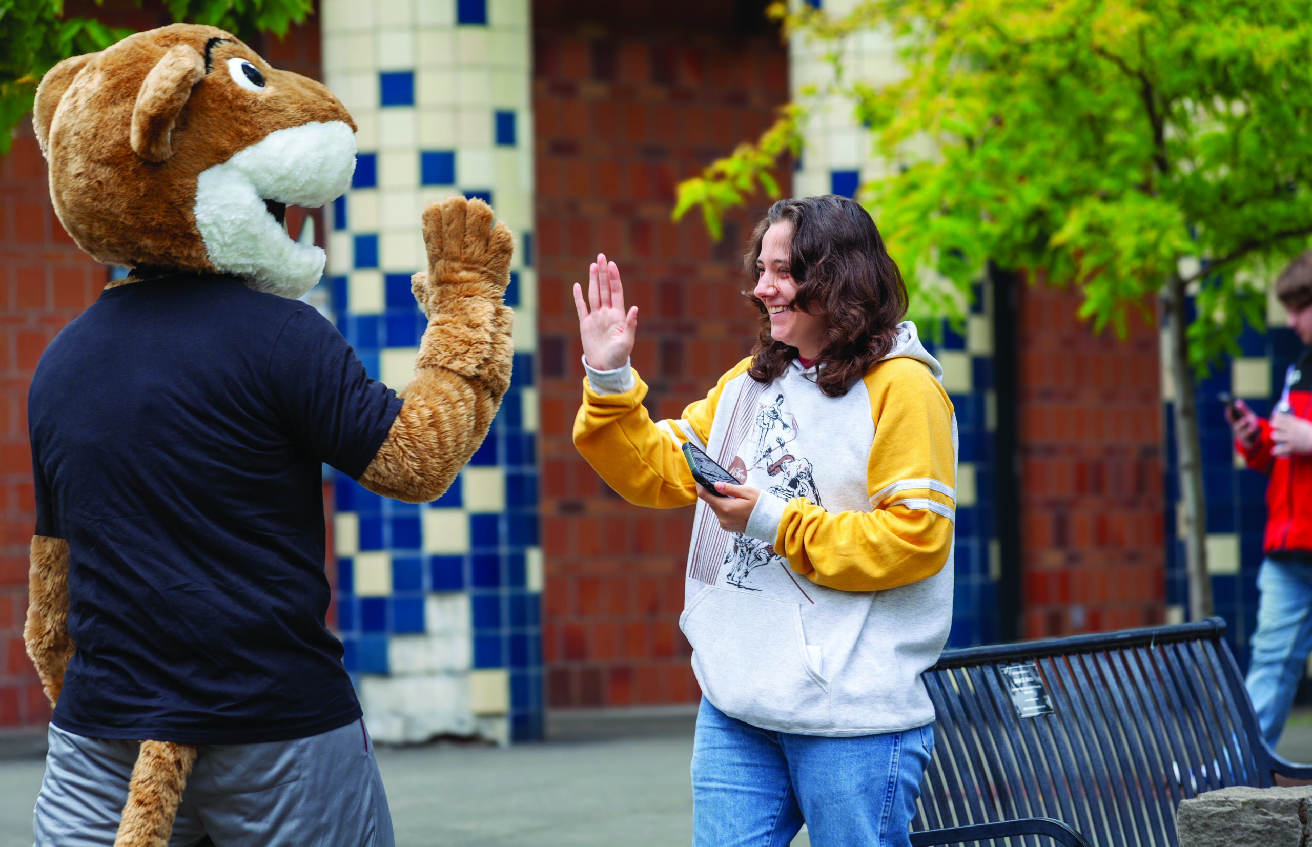 A student high-fiving the WSU Vancouver Cougar mascot outdoors