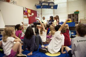 A group of children sitting in a circle listening to an instructor during a WSU Vancouver youth program