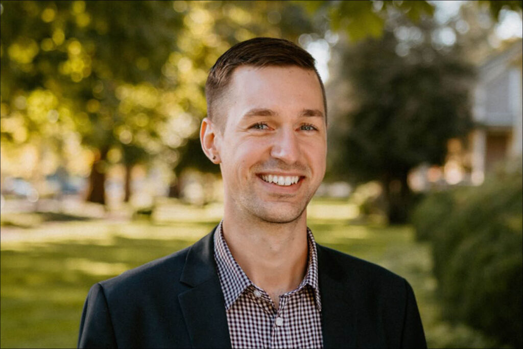 Headshot portrait of a smiling man in a suit jacket