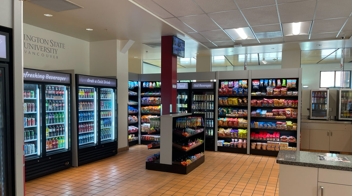 An interior view of an automatic retail cold-beverage display cooler aisle inside a campus store