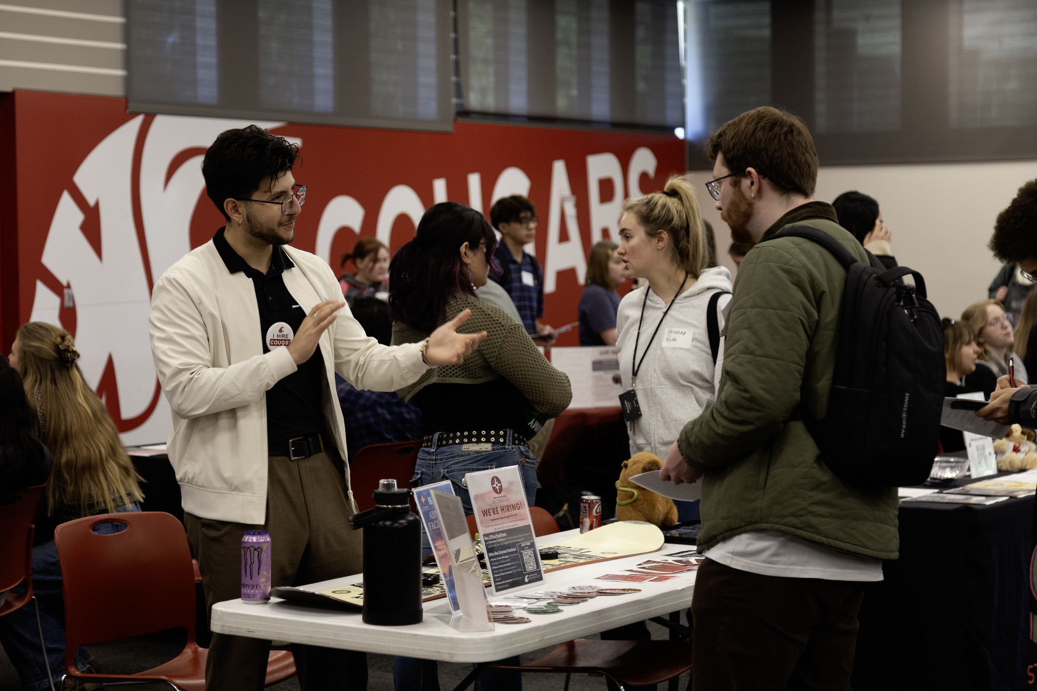A group of students checking out promotional merchandise at a WSU Vancouver indoor booth