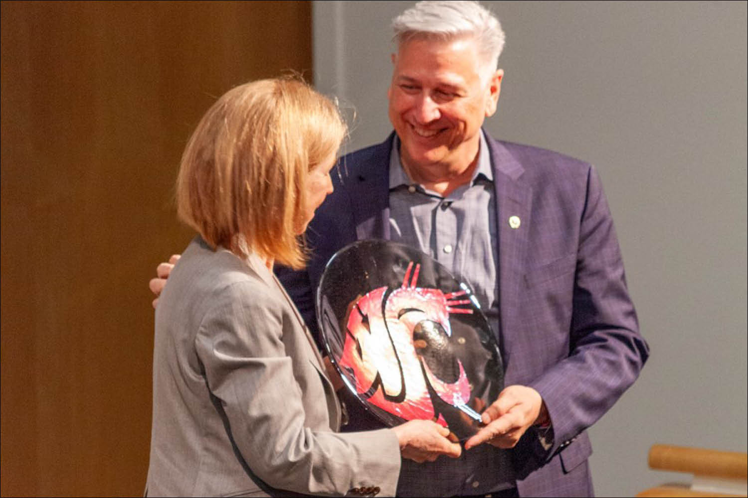 An older man receiving an award or plaque from a colleague