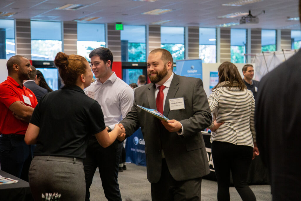 Professionals in business attire networking and shaking hands at a WSU Vancouver career mixer