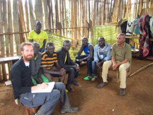 A group sitting together outdoors in a wooded campus area listening to a WSU Vancouver instructor