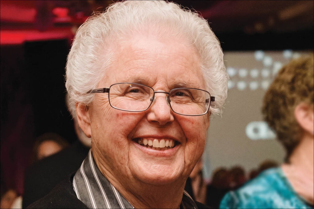 Close-up portrait of a smiling elderly man with white hair and glasses