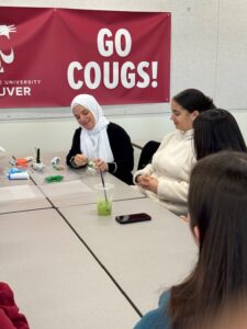 Students collaborating and working around a white table indoors