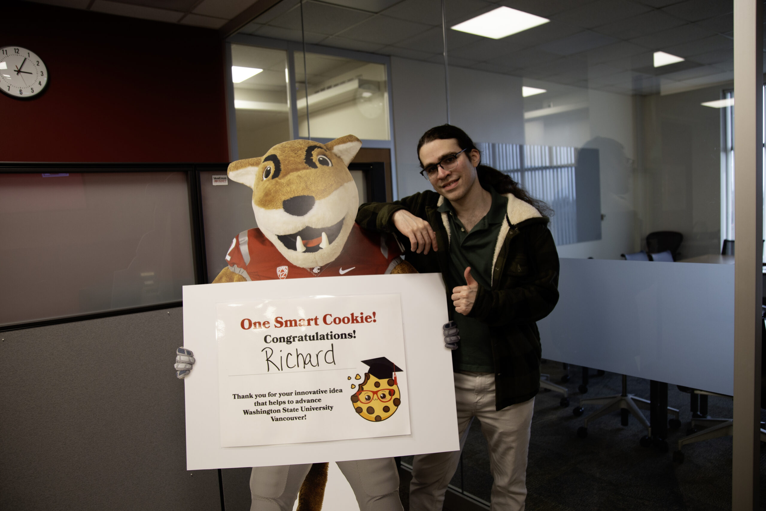 Students posing for a photo with Butch, the WSU mascot, holding a sign on campus