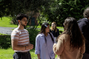 Three students walking and talking along a wooded campus trail