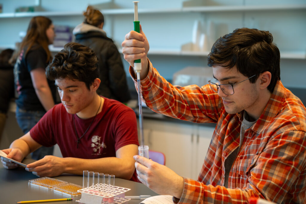 A student using a pipette to transfer liquid samples in a chemistry lab