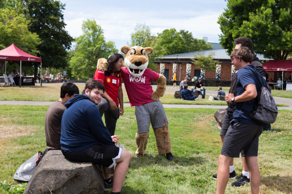 Students interacting with a university cougar mascot outside on a lawn