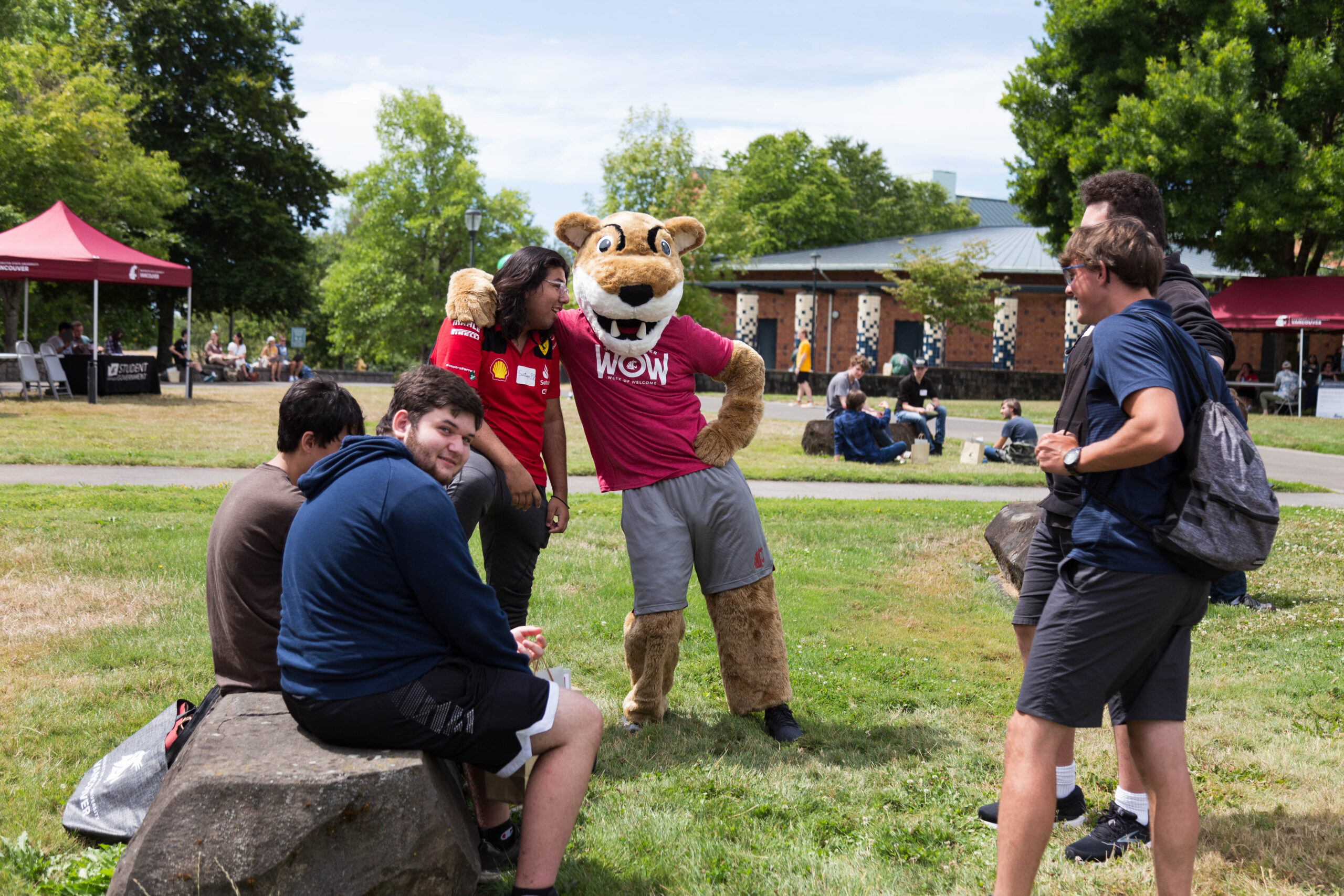 Students interacting with a university cougar mascot outside on a lawn