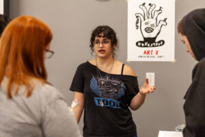 A student presenter speaking with a guest next to an informational poster at WSU Vancouver