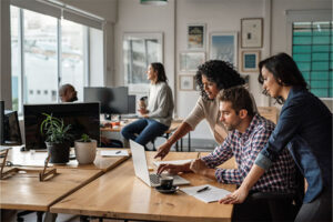 Staff or students collaborating on laptops at a shared workspace inside a WSU Vancouver office