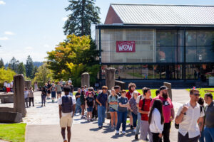 A long line of people waiting outside a campus building named CUB