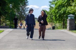 Two young adults walking together along a paved pathway outside