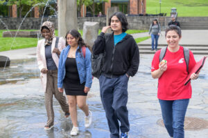 A small group of students walking and talking outdoors on a campus path