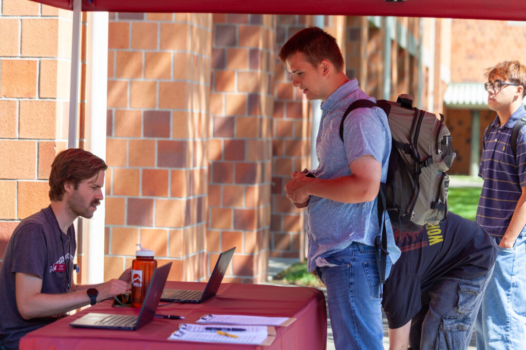 A WSU Vancouver student managing an informational booth with a laptop presentation