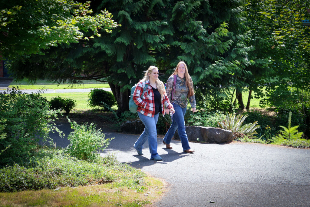 Two WSU Vancouver students walking down a campus path surrounded by greenery
