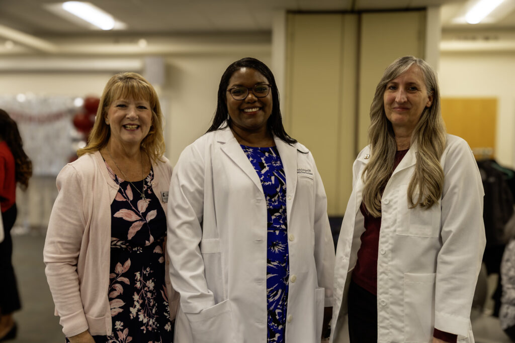 Two professional women wearing white lab coats smiling together at a WSU Vancouver event