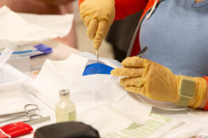 Gloved hands prepping medical supplies or samples during a nursing workshop at WSU Vancouver