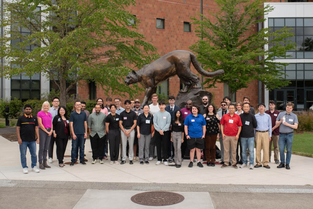A large group of students posing together outside a brick campus building