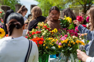 Students selecting colorful flowers from bouquets at an outdoor campus activity at WSU Vancouver