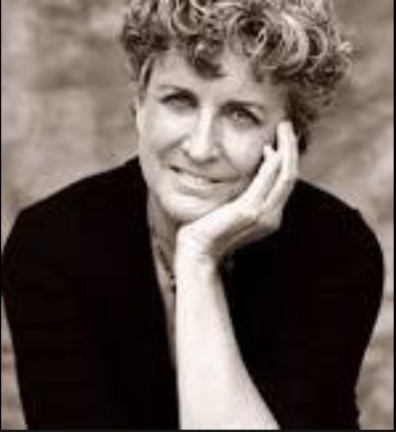 A black and white photo of Barbara with her head in her hand, leaning to the right, and smiling slightly.