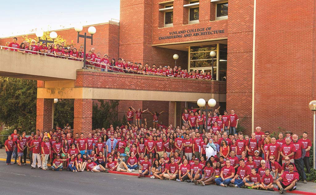 Hundreds of students, staff, and faculty wearing crimson t-shirts posing for a group photo outside the Voiland College.