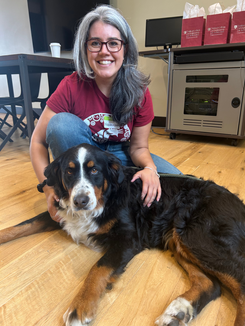 Smiling woman kneeling next to a dog.
